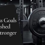 Langhantel im Squat-Rack mit Sicherheitsablagen, daneben Bandagen und Gewichthebergürtel