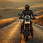 Motorradfahrer in kompletter Schutzkleidung mit Integralhelm neben seinem Motorrad auf einer Landstraße