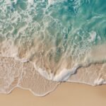 Luftaufnahme eines Sandstrands mit erkennbarer Rippströmung, die zwischen brechenden Wellen aufs offene Meer zieht